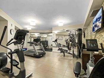 a gym with various exercise equipment and a tv on the wall